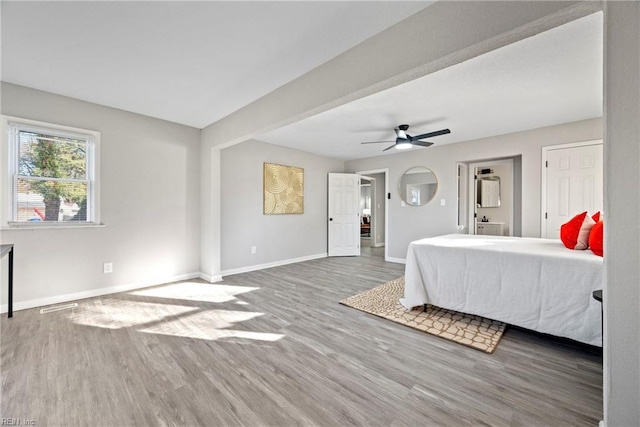 bedroom with a ceiling fan, visible vents, baseboards, and wood finished floors