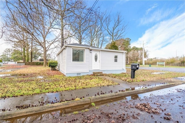 view of front of home with crawl space and fence