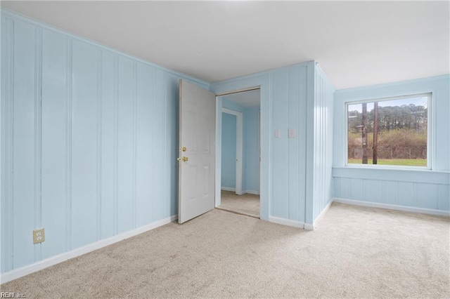 unfurnished bedroom featuring light carpet and a decorative wall