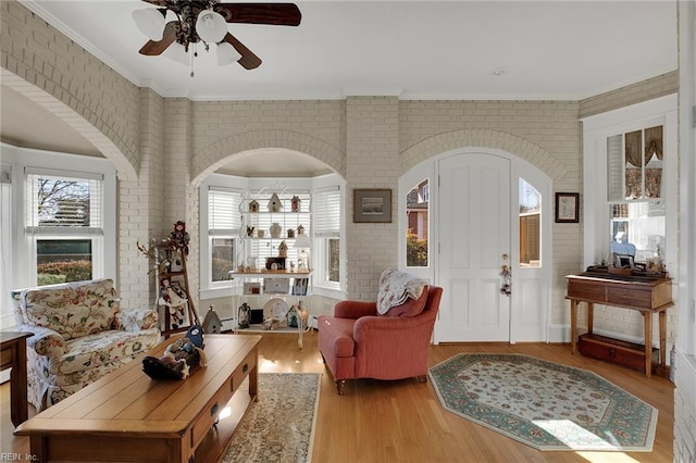 living area featuring light wood finished floors, brick wall, and ornamental molding