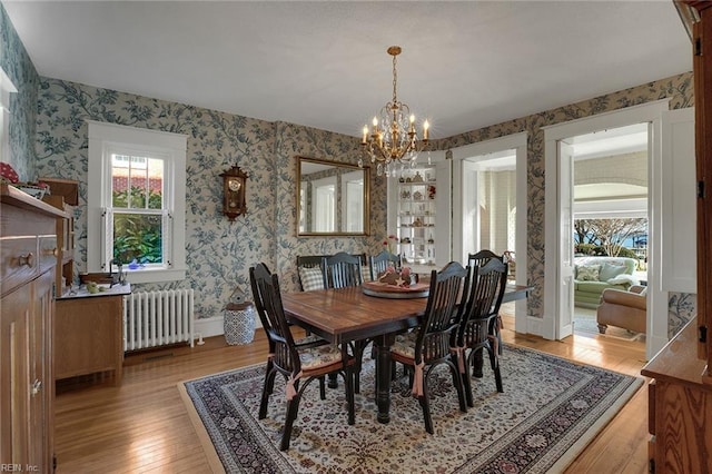 dining space with a notable chandelier, baseboards, radiator, light wood finished floors, and wallpapered walls