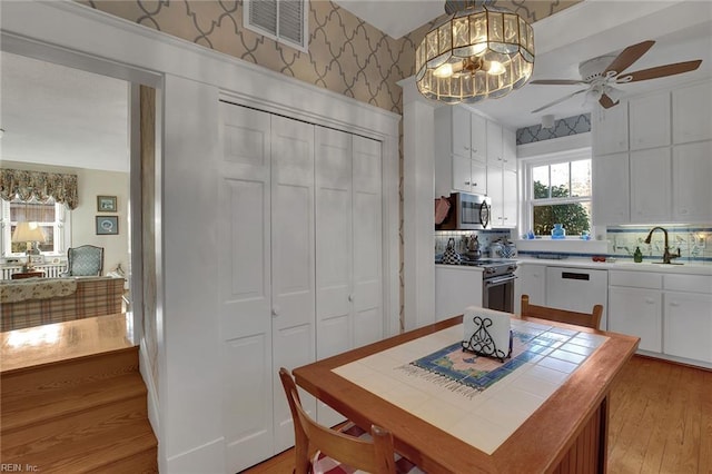 dining space featuring wallpapered walls, light wood-style flooring, visible vents, and ceiling fan