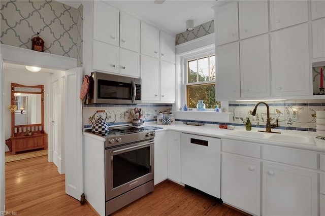 kitchen featuring a sink, white cabinets, stainless steel appliances, and light countertops