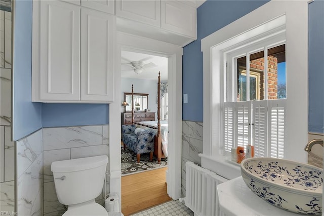 bathroom with radiator, a healthy amount of sunlight, tile walls, and wainscoting