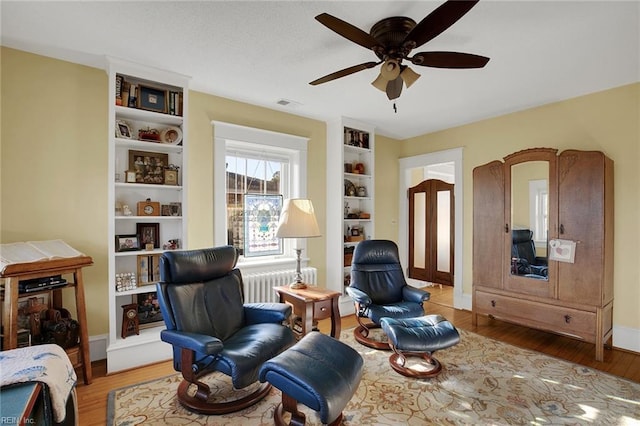 sitting room featuring radiator, visible vents, baseboards, and wood finished floors