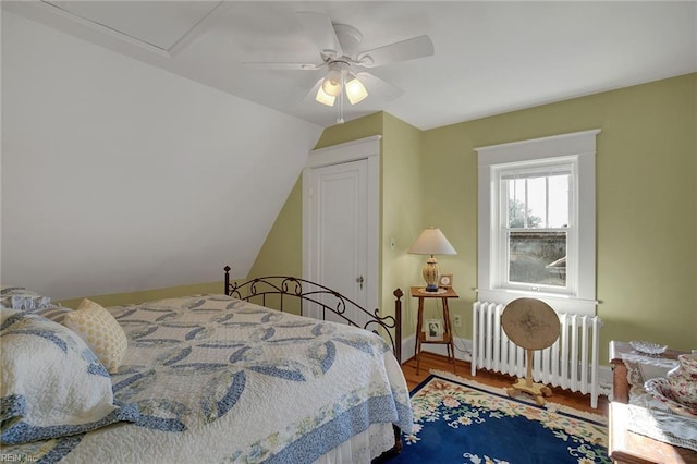 bedroom featuring radiator, a ceiling fan, vaulted ceiling, wood finished floors, and baseboards