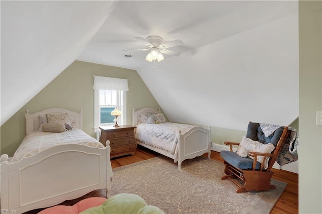 bedroom with lofted ceiling, ceiling fan, a water view, and wood finished floors