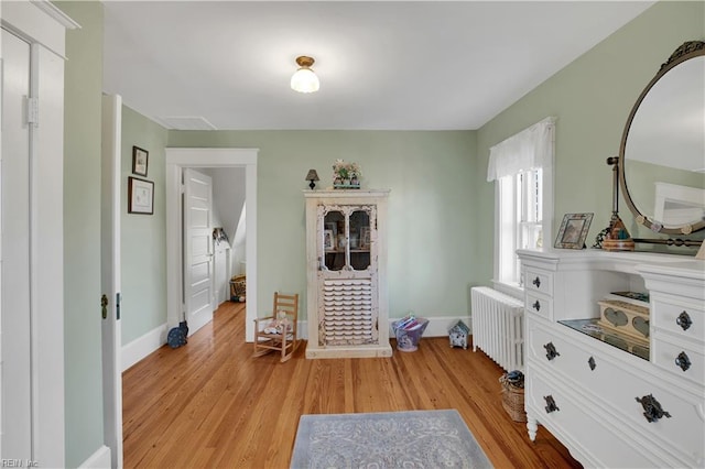 bedroom with light wood finished floors, radiator heating unit, and baseboards