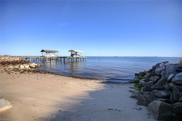 view of dock featuring a water view and a beach view