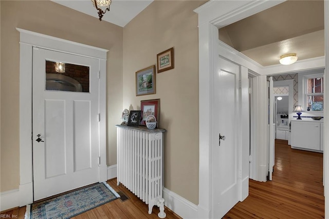 entrance foyer with radiator, baseboards, and wood finished floors