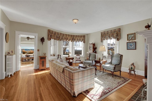 living area with radiator heating unit, wood finished floors, and baseboards