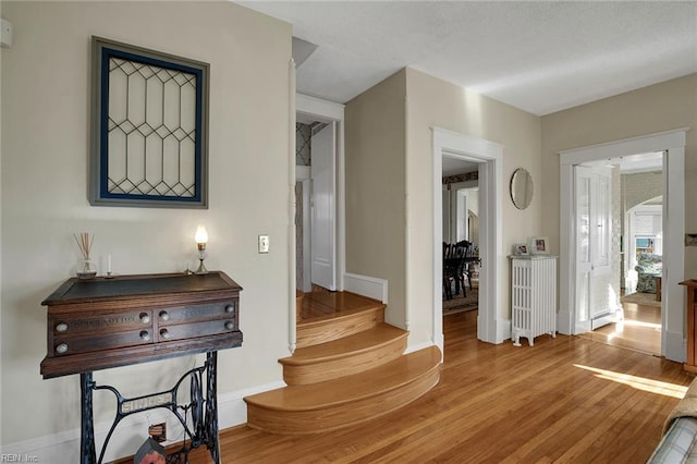 hall with stairs, baseboards, and wood finished floors