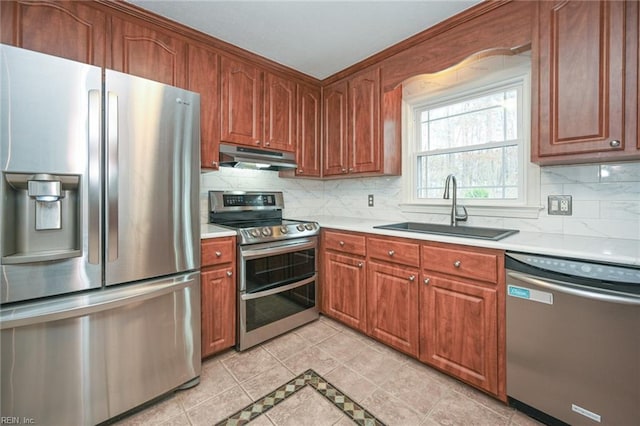 kitchen featuring under cabinet range hood, a sink, light countertops, appliances with stainless steel finishes, and decorative backsplash