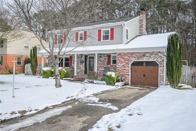 traditional home featuring a garage, brick siding, driveway, and a chimney