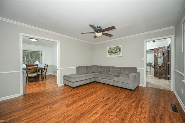 living area with visible vents, crown molding, and wood finished floors