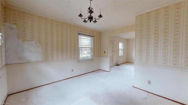 empty room featuring light colored carpet, crown molding, a notable chandelier, and wallpapered walls