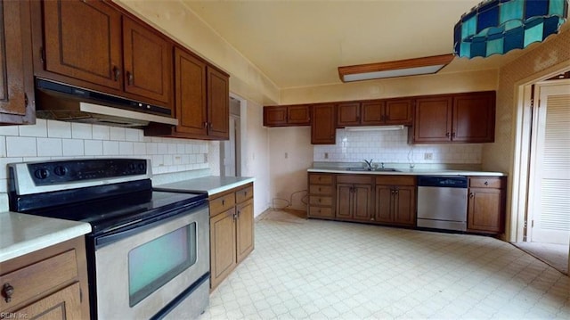 kitchen with light countertops, appliances with stainless steel finishes, a sink, and under cabinet range hood