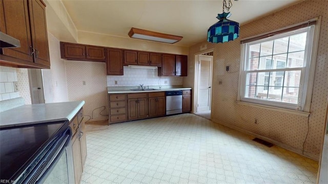 kitchen featuring light countertops, hanging light fixtures, dishwasher, and wallpapered walls