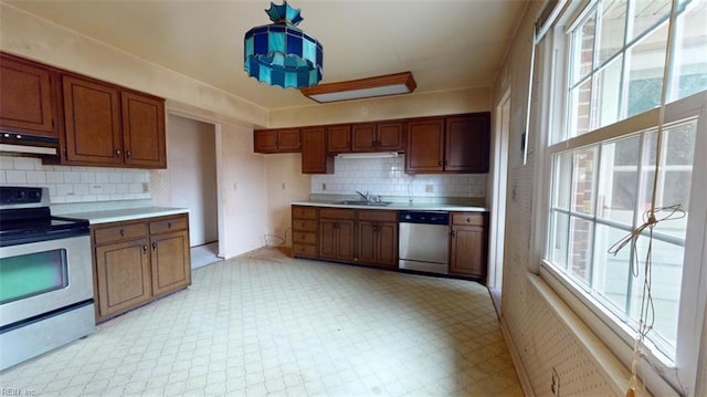 kitchen featuring under cabinet range hood, stainless steel appliances, a sink, light countertops, and light floors