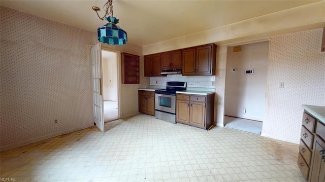 kitchen featuring wallpapered walls, stainless steel electric stove, light countertops, and decorative light fixtures