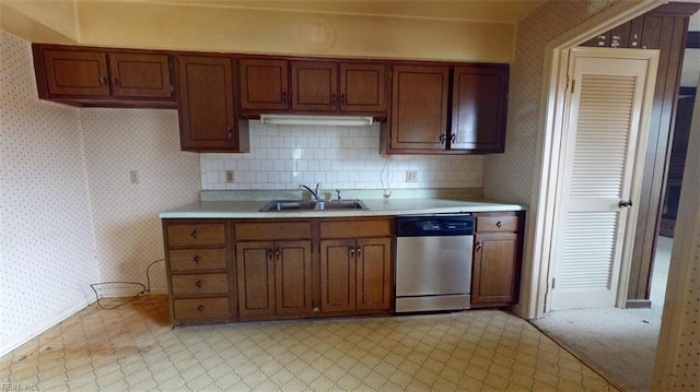 kitchen with wallpapered walls, dishwasher, brown cabinets, light countertops, and a sink