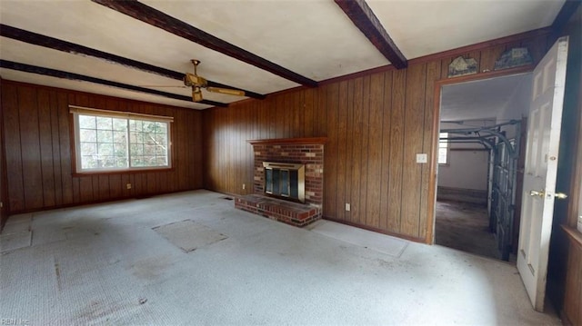 unfurnished living room featuring wood walls, beamed ceiling, and a fireplace