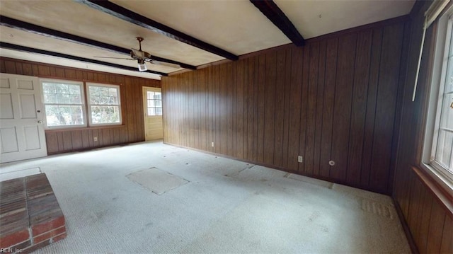 unfurnished room with light carpet, beamed ceiling, wooden walls, and ceiling fan