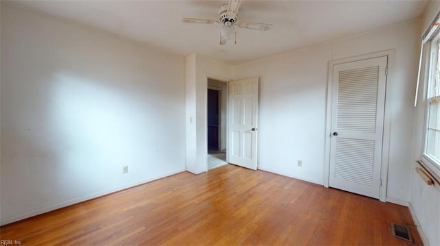 unfurnished bedroom with ceiling fan, a closet, light wood-type flooring, and visible vents