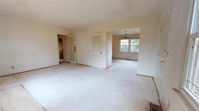 empty room featuring light carpet, visible vents, and a notable chandelier