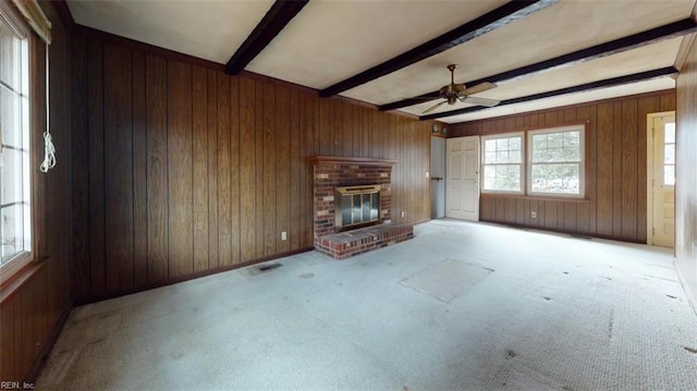 unfurnished living room with light carpet, a fireplace, beamed ceiling, and wood walls