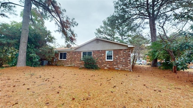 view of side of home with a yard, brick siding, and a chimney