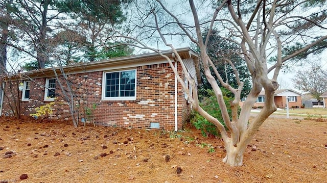 view of home's exterior with crawl space and brick siding