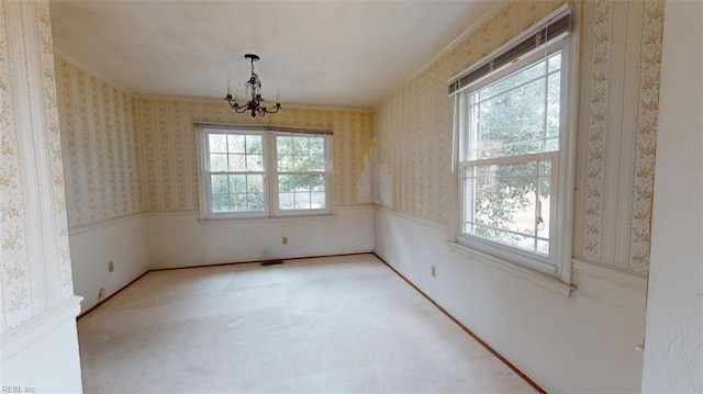 spare room with a chandelier, ornamental molding, carpet flooring, and wallpapered walls