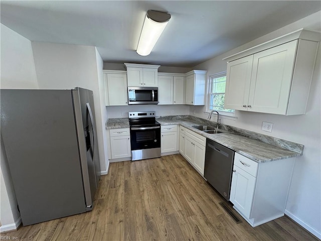 kitchen featuring a sink, visible vents, white cabinetry, appliances with stainless steel finishes, and light stone countertops