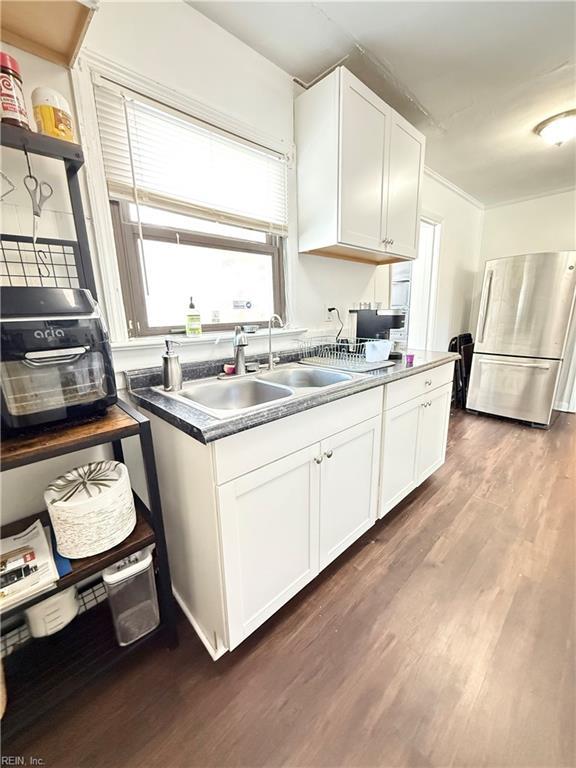 kitchen featuring dark wood-type flooring, a sink, white cabinetry, freestanding refrigerator, and dark countertops