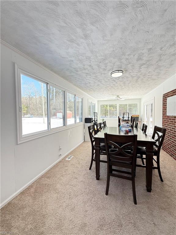 carpeted dining area with baseboards, visible vents, and a textured ceiling