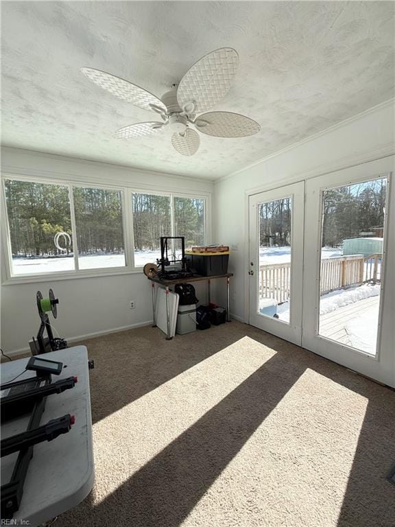 interior space with a textured ceiling, dark colored carpet, a ceiling fan, and baseboards