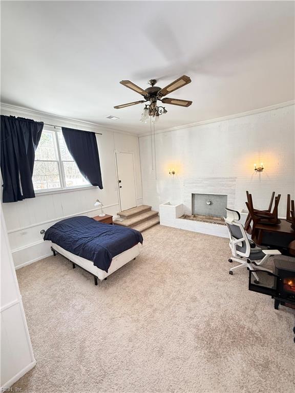 carpeted bedroom featuring ornamental molding, a brick fireplace, and a ceiling fan