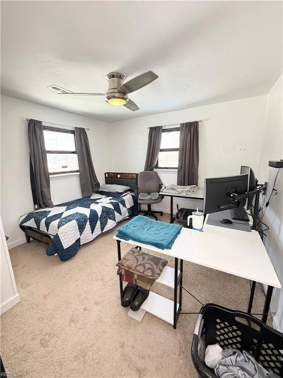 bedroom featuring light carpet, ceiling fan, multiple windows, and baseboards