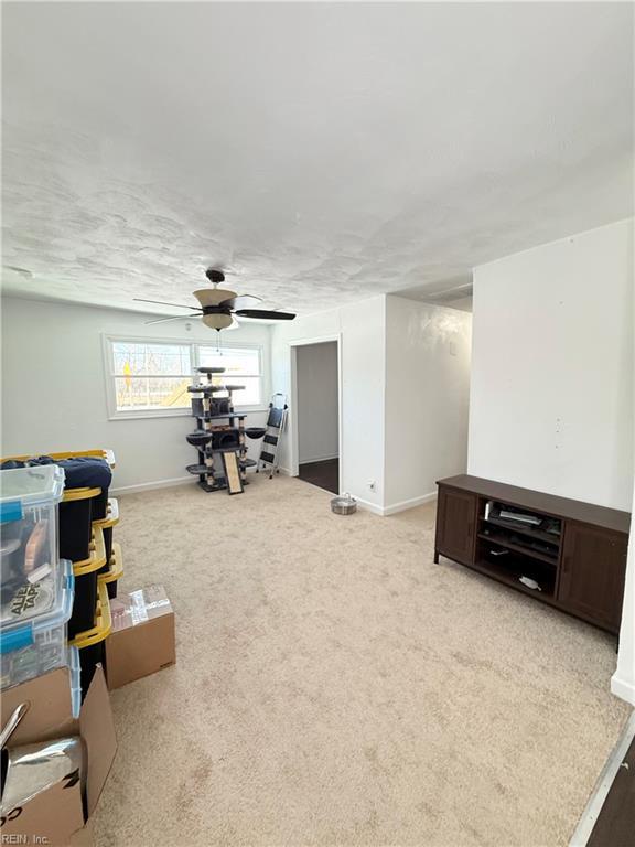 interior space with ceiling fan, baseboards, and light colored carpet