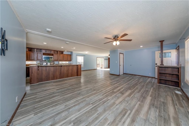 unfurnished living room featuring a ceiling fan, a textured ceiling, baseboards, and wood finished floors