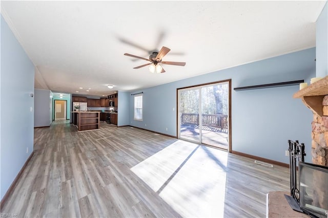 unfurnished living room with light wood-style flooring, visible vents, baseboards, and ceiling fan