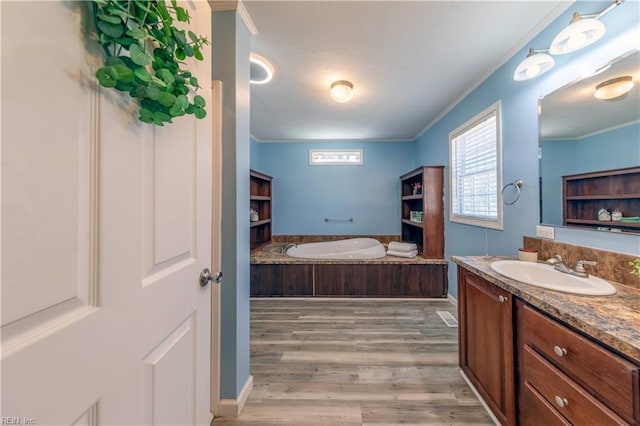 bathroom featuring a bath, wood finished floors, crown molding, and vanity