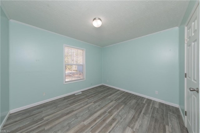 spare room with crown molding, a textured ceiling, baseboards, and wood finished floors