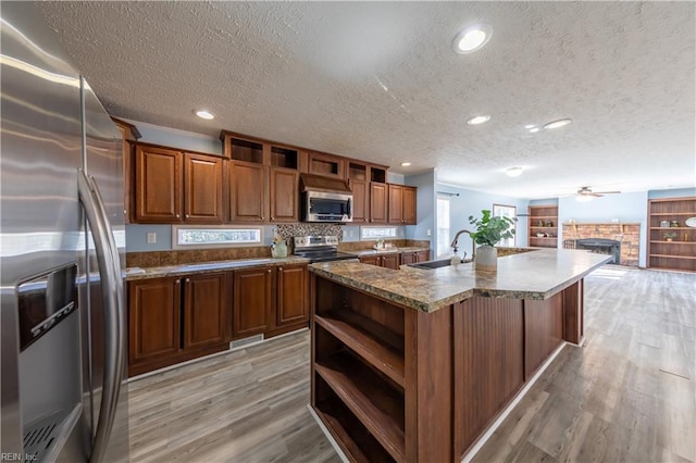 kitchen featuring open shelves, appliances with stainless steel finishes, a sink, and light wood-style floors