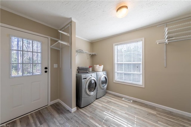 laundry room with a textured ceiling, laundry area, baseboards, independent washer and dryer, and light wood finished floors