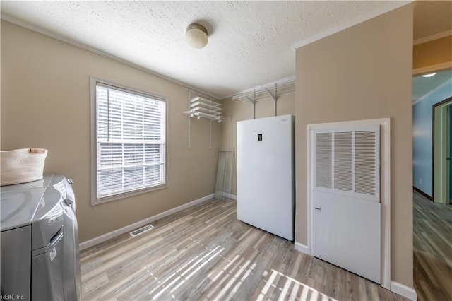 laundry area featuring a textured ceiling, laundry area, independent washer and dryer, and light wood-style flooring