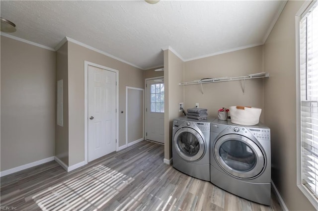 washroom with washer and clothes dryer, ornamental molding, a textured ceiling, light wood-type flooring, and baseboards