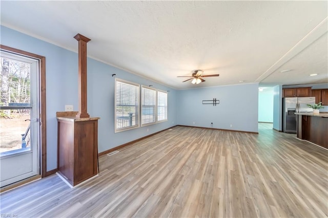 unfurnished living room with ornamental molding, light wood-type flooring, a ceiling fan, and baseboards