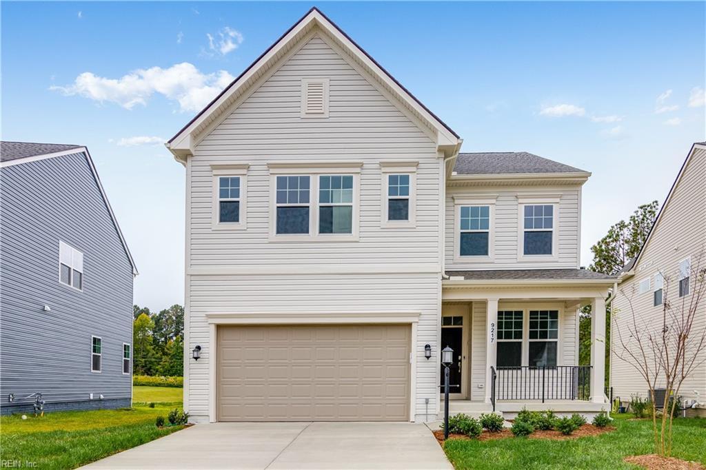 traditional-style house featuring a garage, covered porch, concrete driveway, and a front yard